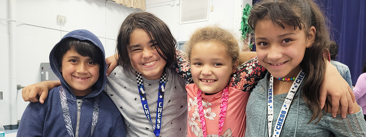 Four happy students posing for a picture at the chess tournament